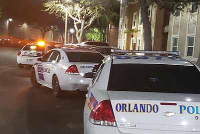 Orlando police vehicles responding to an incident outside an apartment complex at night.
